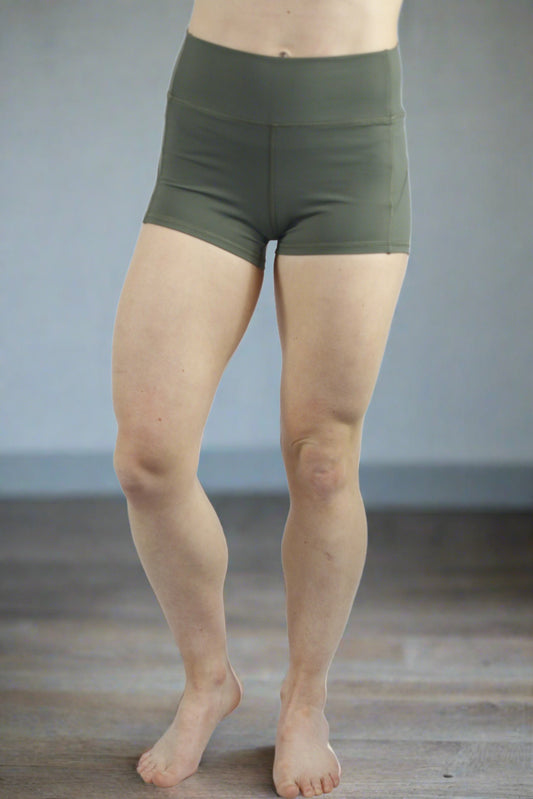 A Girl wearing a green pair of CrossFit shorts in a CrossFit studio